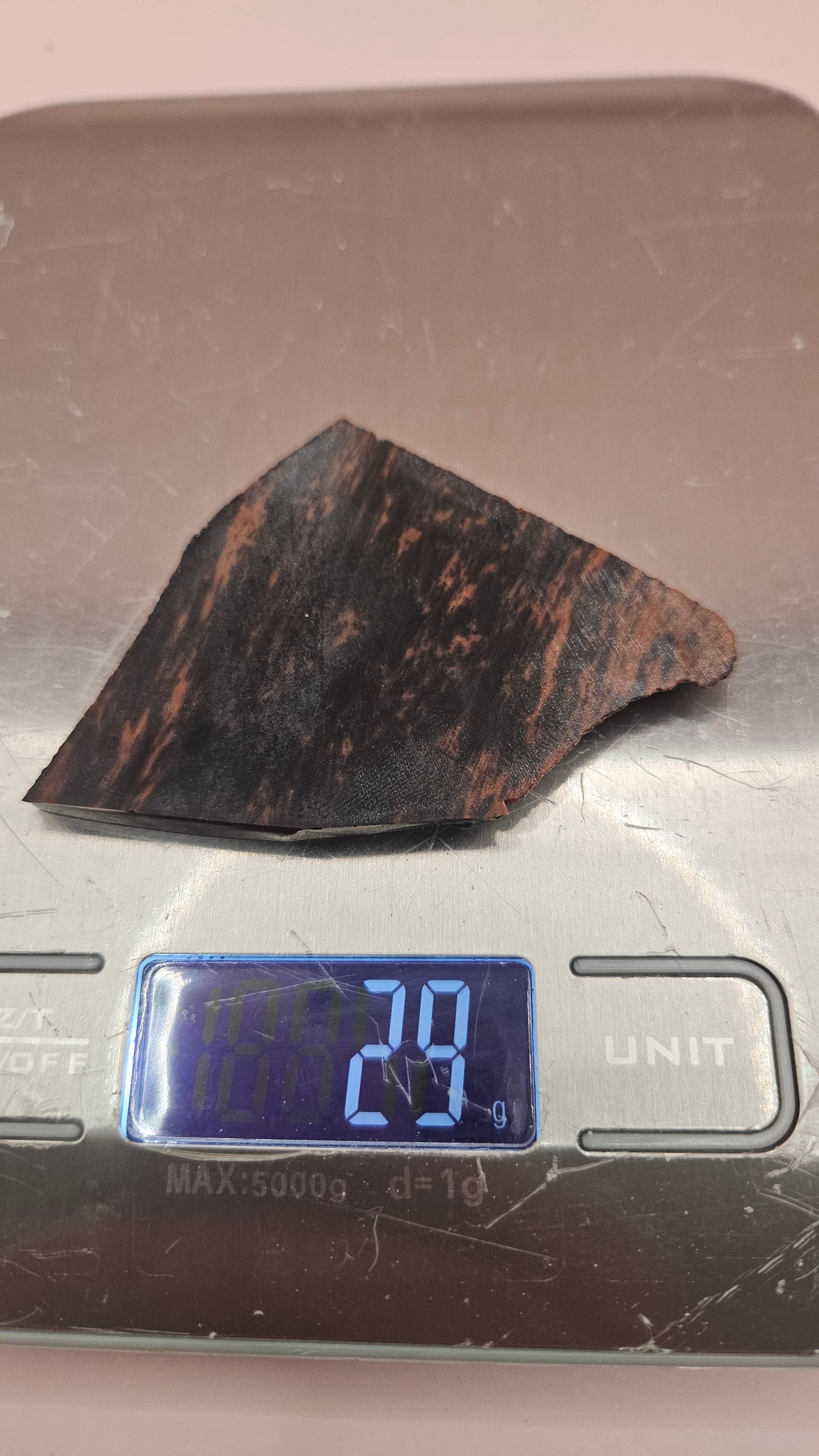 Polished Mahogany Obsidian slab with reddish-brown and black bands, weighing 29 grams, shown against a pink background.