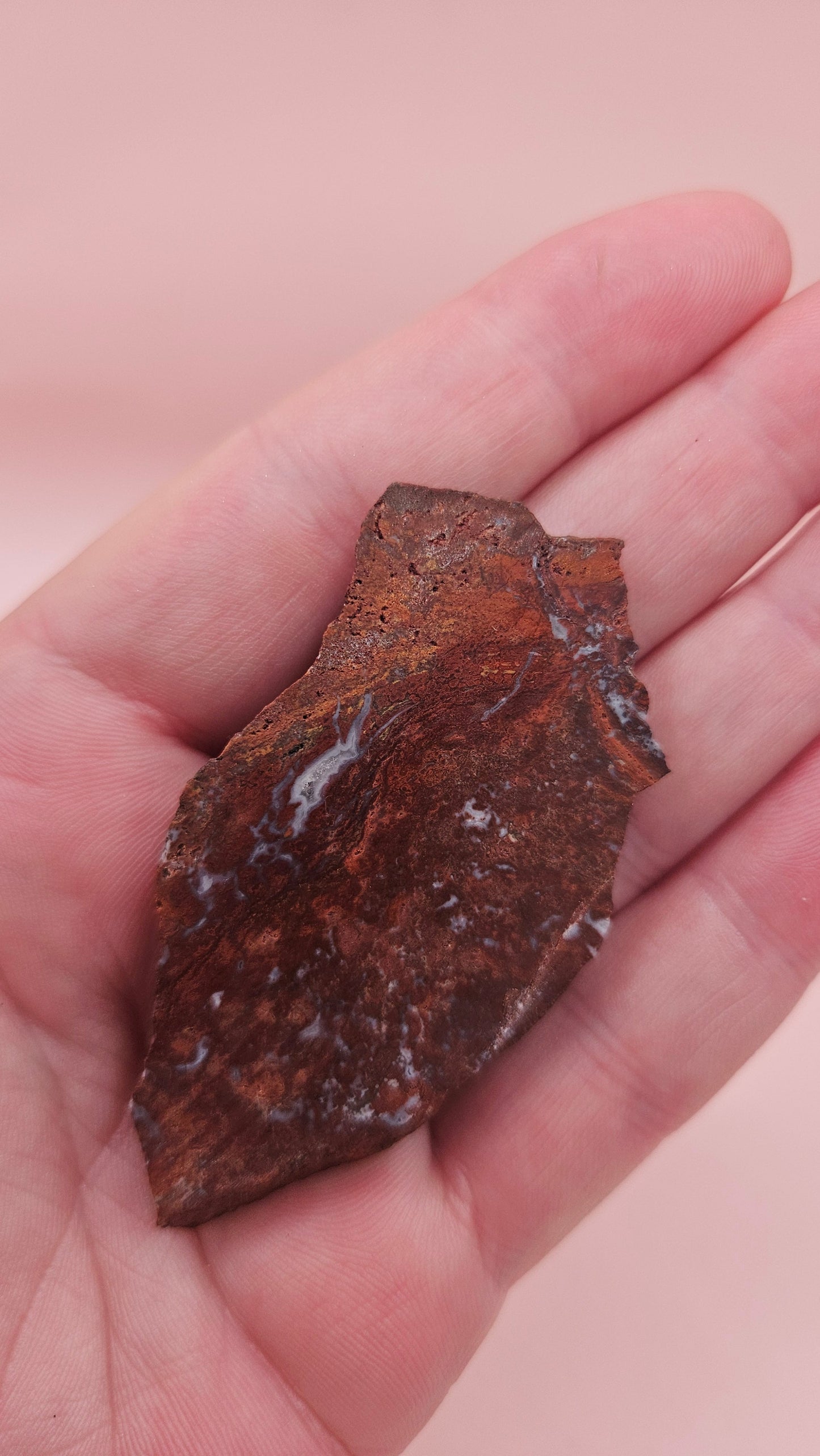 Moss Agate slab 22g, reddish with blue-white moss-like inclusions, 2.6x1.3 inches, photographed on pink background.