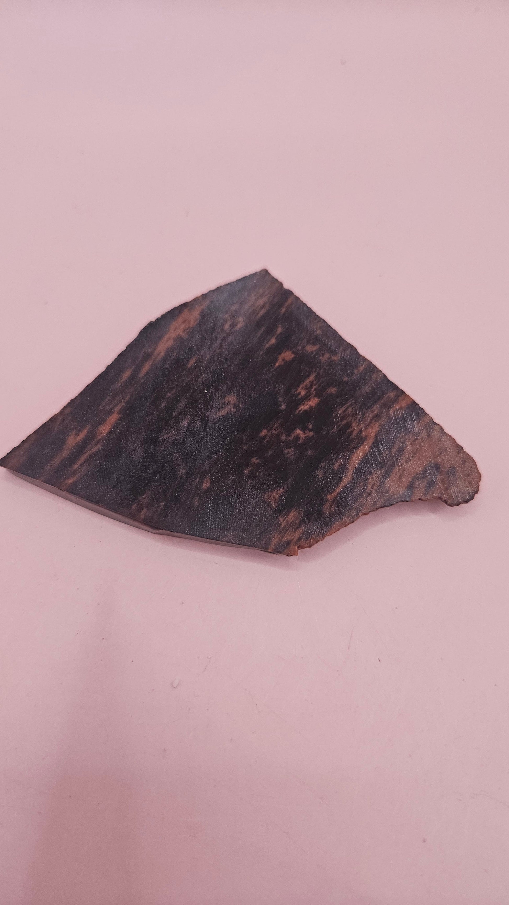 Polished Mahogany Obsidian slab with reddish-brown and black bands, weighing 29 grams, shown against a pink background.