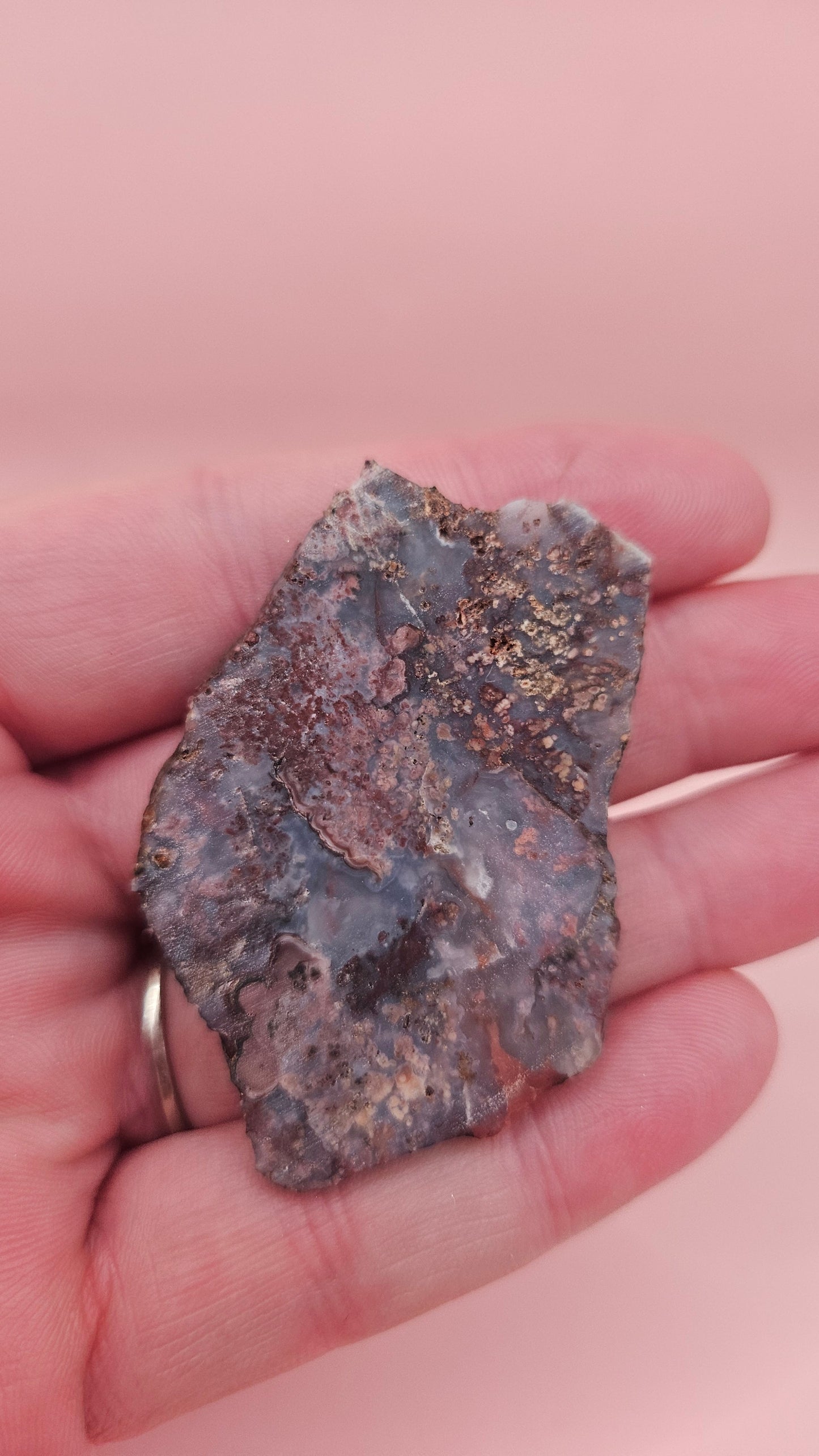 18g Moss Agate slab featuring lavender, gold, and reddish inclusions with rough edges, 2.1x1.4 inches, shown in hand.