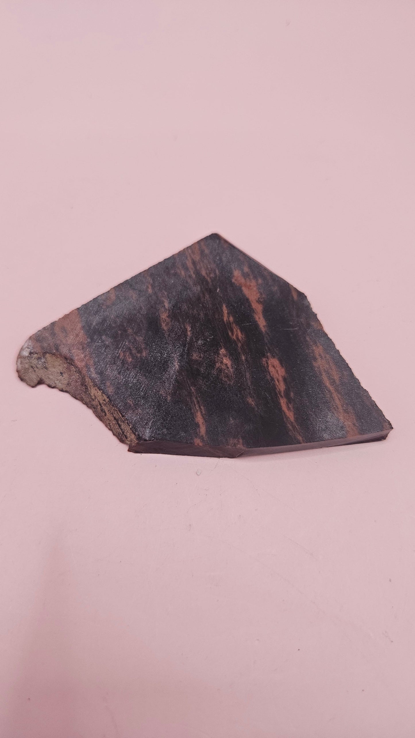 Polished Mahogany Obsidian slab with reddish-brown and black bands, weighing 29 grams, shown against a pink background.