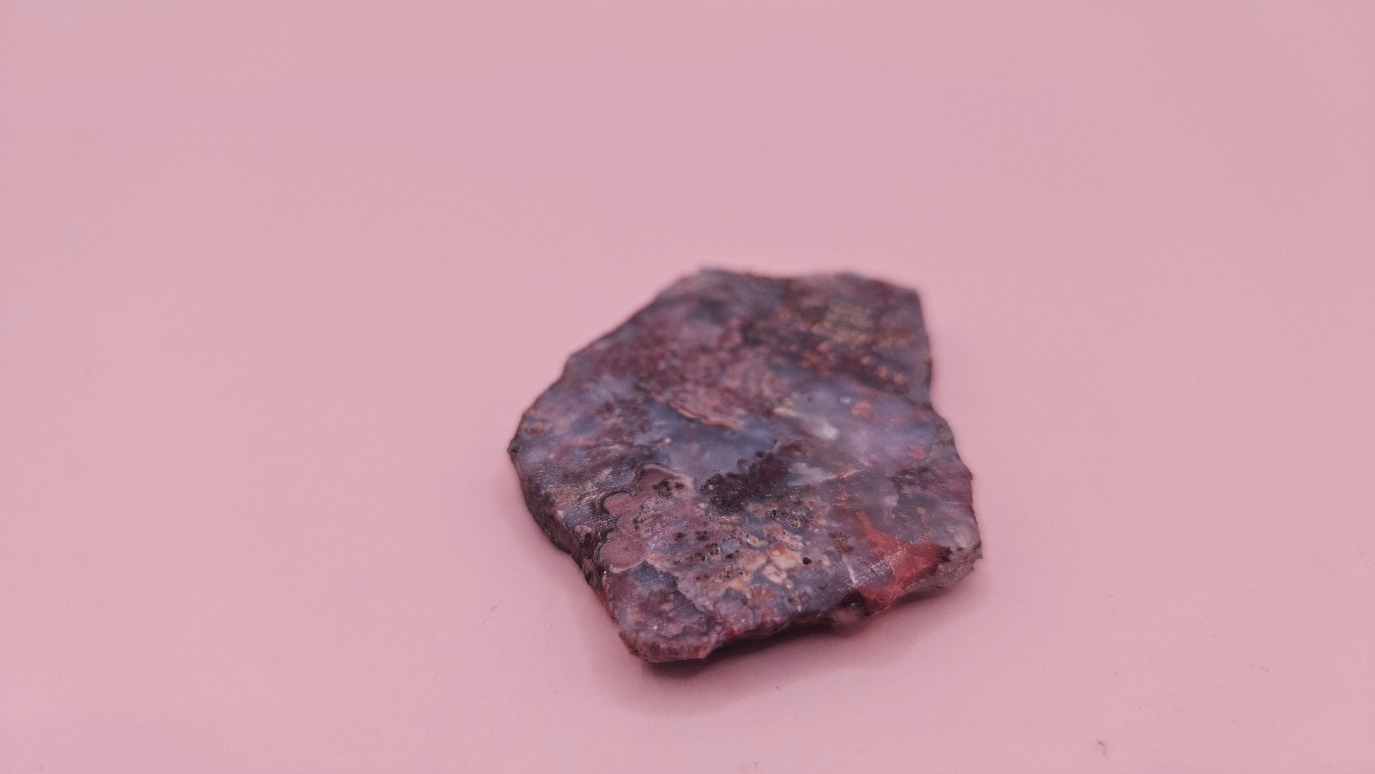 18g Moss Agate slab featuring lavender, gold, and reddish inclusions with rough edges, 2.1x1.4 inches, shown in hand.